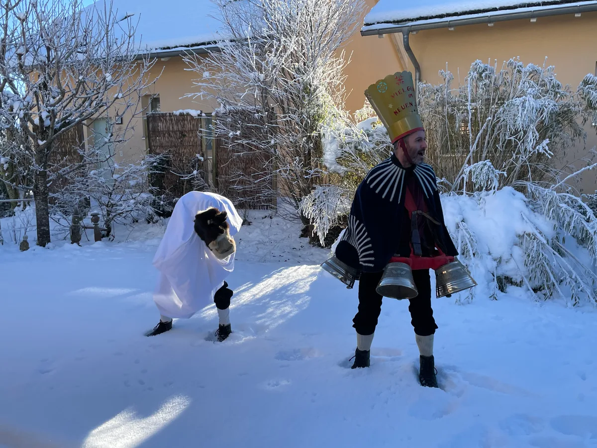 Ein Silvesterchlaus und ein Schnappesel tanzen im Schnee.